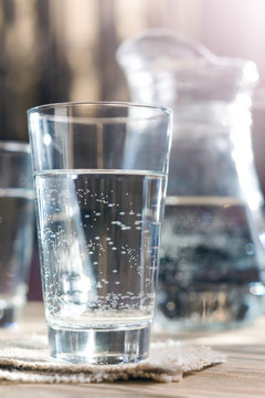 Glass of water against the background of a decanter. With light effects. Selective focus. Shallow DOF. 