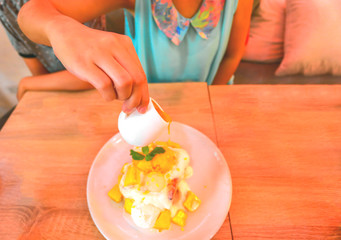 Pouring sauce onto delicious dessert with ice cream in bowl