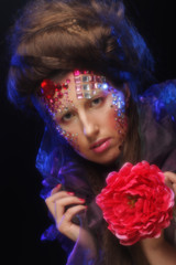 young woman with artistic visage holding big red flower