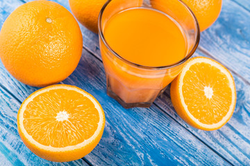 Freshly squeezed citrus juice. Oranges fruit and orange juice on a blue wooden background. Place for the text.