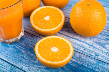 Freshly squeezed citrus juice. Oranges fruit and orange juice on a blue wooden background. Place for the text.
