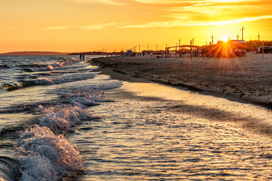 Beautiful scenic landscape of sandy Blaga Beach at Anapa resort on Black Sea coast with surfing waves and people on seashore. Summer sunset seaside scenery