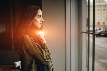 Obraz premium Fashion consept: beatiful young girl with long hair, glasses, red lips standing near modern wall wearing in green suit and grey jeans. She wanted talking on phone.