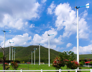 eco power  wind turbines generating electricity clean energy  on green grass with mountain and...