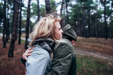 A loving guy with a girl is walking through the woods in the rain.