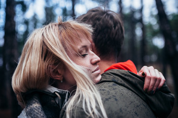 A loving guy with a girl is walking through the woods in the rain.