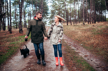 Family walks with a dog in the forest near a river in the rain