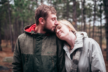A loving guy with a girl is walking through the woods in the rain.