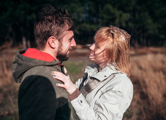 A loving guy with a girl is walking through the woods in the rain.