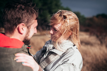A loving guy with a girl is walking through the woods in the rain.