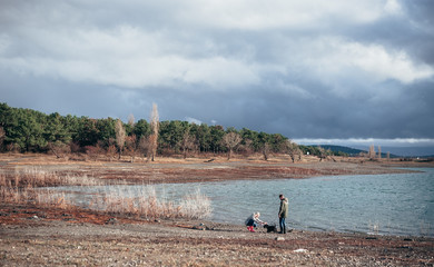 Family walks with a dog in the forest near a river in the rain