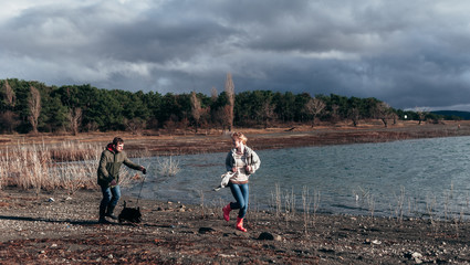Family walks with a dog in the forest near a river in the rain