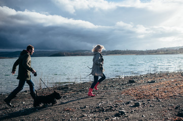 Family walks with a dog in the forest near a river in the rain
