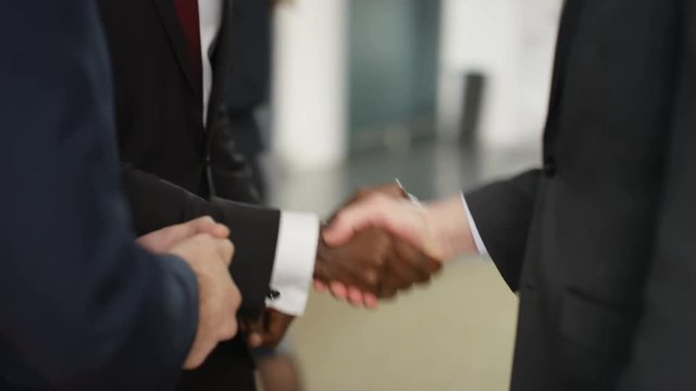  Cheerful businessmen shaking hands & having conversation in modern office
