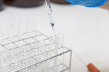 chemist dropping the clear reagent into test tube for reaction testing in chemical laboratory, with...