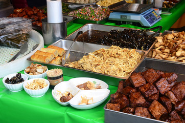Plates of cooked food in traditional market for sale.