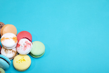 Tasty different colored macarons on blue background.