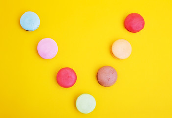 Tasty different colored macarons on yellow background