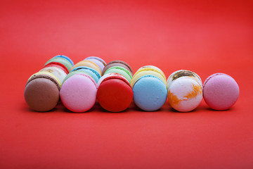 Tasty different colored macarons  on red background.