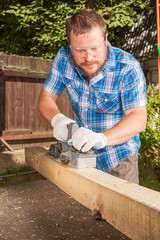 Carpenter chipping the wooden plank