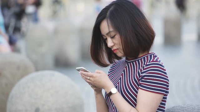 profile of charming chinese woman using smartphone- outdoor