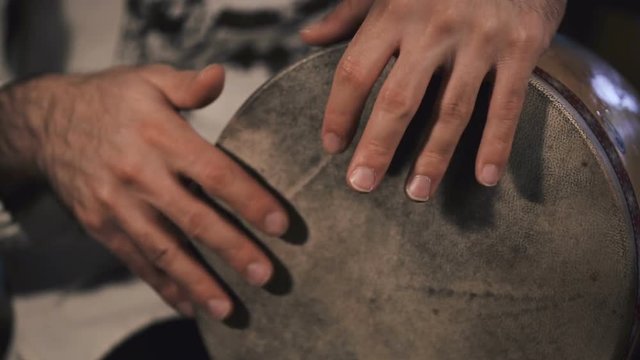 close up shot of man drumming out a beat on an arabic percussion drum named Tombak at home.