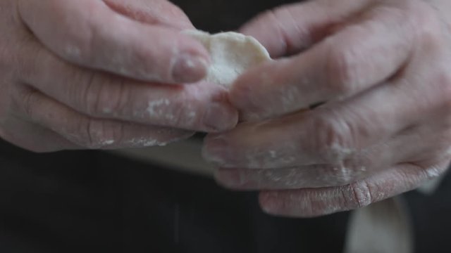 Close-up view of two woman's hands making meat dumplings.