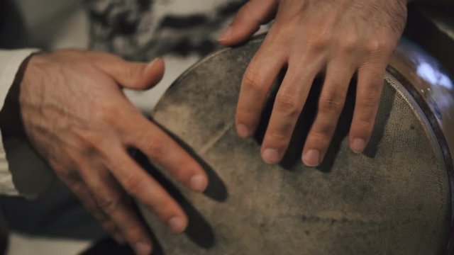 close up shot of man drumming out a beat on an arabic percussion drum named Tombak at home.