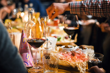 Restaurant or bar table with plates of appetizers and wine. People talking on background. Toned picture
