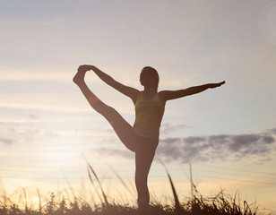 Obraz premium Silhouette young woman practicing yoga at backyard