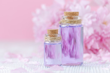 beautiful spa composition with two bottles of essential oils, fresh flowers on pink background, selective focus
