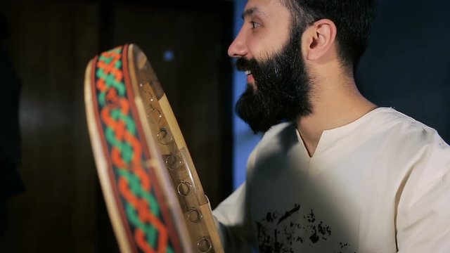 close up shot of man drumming out a beat on an arabic percussion drum named Dayereh at home.