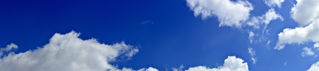 Panorama of spring, summer clouds on a blue sunny sky, background.