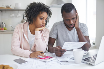 Stressed african american couple looking frustrated, having no money to pay off their debts,...