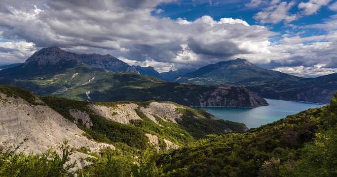 Serre-Poncon with the lake and Grand Morgon Pic in summer. Hautes-Alpes time-lapse with passing clouds, Southern French Alps, France