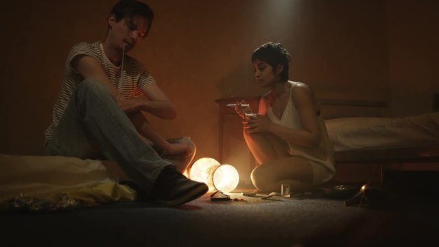  Drug addict couple in gloomy apartment, woman injecting boyfriend in the arm