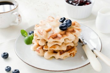 Belgian waffles served with honey, blueberries, jam and cup of coffee