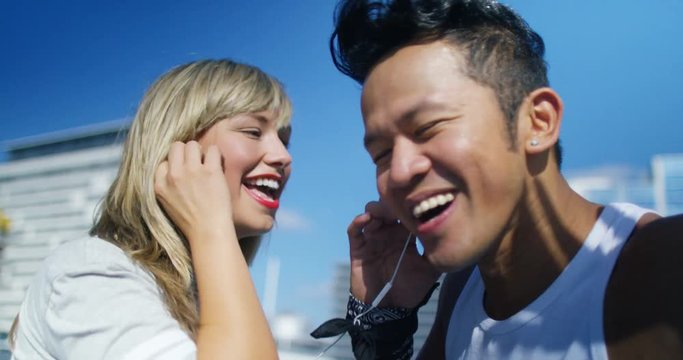  Young urban couple listening to music through earphones outdoors in the city.