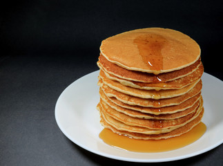 Stack of Fresh Homemade Pancakes with Maple Syrup, Served on White Plate, Black Background 