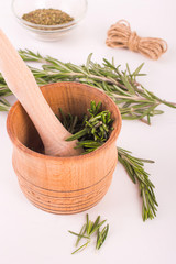 Rosemary in a wooden mortar on a white background