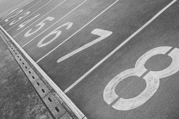 Running track with numbers from 1 to 8. Shot in a unique angle. A gutter along the track. Black and...