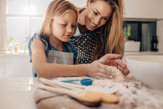 Mother teaching her daughter to make dough