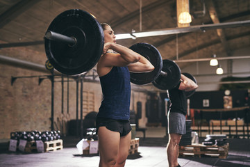 Sportive people standing with barbells on shoulders