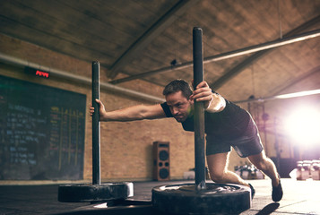 Sportive man pushing weight disks in gym