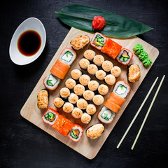 Fototapeta na wymiar Japanese food - sushi rolls, soy sauce and chopsticks on a black background. Top view. Flat lay. Restaurant food.