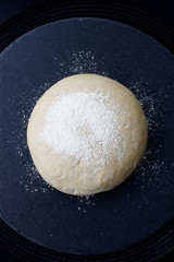 Homemade organic Dough for pizza or bread on black slate stone plate 