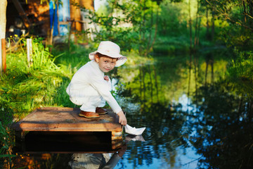 girl plays with paper boat in the river