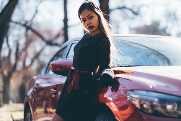 Young beautiful girl in black dress with the red sport car