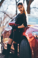 Fototapeta na wymiar Young beautiful girl in black dress with the red sport car