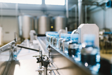Water factory - Water bottling line for processing and bottling pure spring water into small blue bottles. Selective focus. 